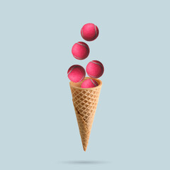 A pink tennis balls flies out of an ice cream cone on pastel blue background. Sports concept. Tennis concept.