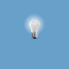 Collage made out of white tooth and incandescent light bulb on blue background. Dental concept....