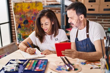 Middle age man and woman artists drawing on notebook using touchpad at art studio