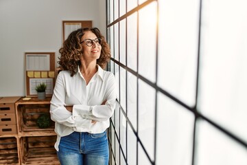 Middle age hispanic woman smiling confident with arms crossed gesture at office