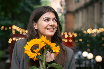 Naklejka premium Portrait of a young woman with a bouquet of sunflowers.