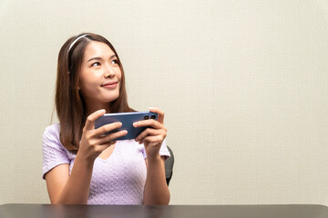 Pretty and cute Asian teenage girl wearing purple shirt brown hair wearing a headband playing on...