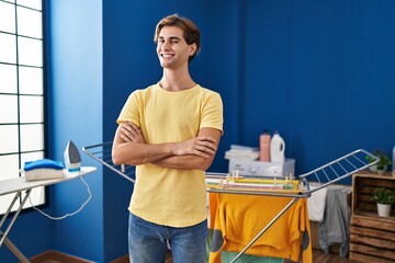 Young man doing laundry winking looking at the camera with sexy expression, cheerful and happy face.