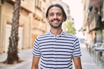 Young hispanic man with beard outdoors at the city with a happy and cool smile on face. lucky person.