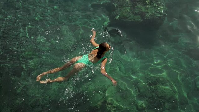 slow motion top view of sexy stunning woman with nise buttocks in green swimsuit floating in clear turquoise water of mediterranean sea. vacation and wellness, Summer Season Fethiye, Turkey