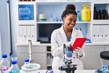 African american woman scientist using touchpad working at laboratory
