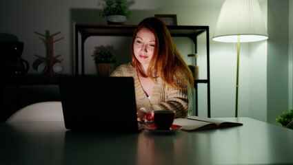 Fototapeta na wymiar Young redhead woman using laptop studying at home