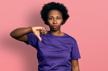 African american woman with afro hair wearing casual purple t shirt looking unhappy and angry...