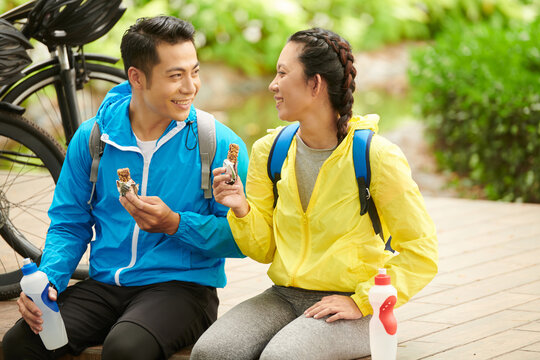 Happy young couple eating energy bars after bicycle ride to get more energy