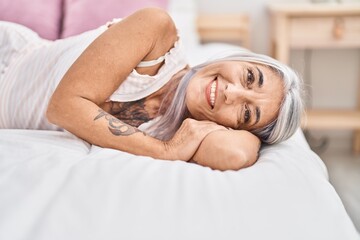 Obraz na płótnie Canvas Middle age grey-haired woman smiling confident lying on bed at bedroom
