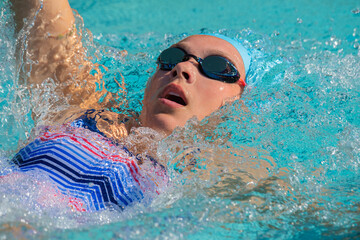 Close up of femaile athlete swimming backstroke