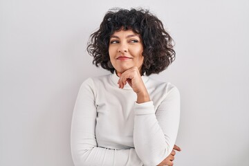 Fototapeta na wymiar Hispanic woman with curly hair standing over isolated background with hand on chin thinking about question, pensive expression. smiling and thoughtful face. doubt concept.