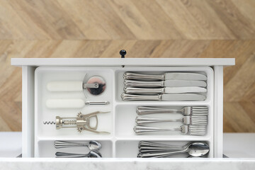 Clean silverware at tray in open white drawer