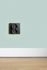 Socket in black plastic frame on green wall