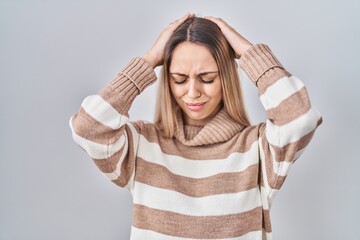 Young blonde woman wearing turtleneck sweater over isolated background suffering from headache desperate and stressed because pain and migraine. hands on head.