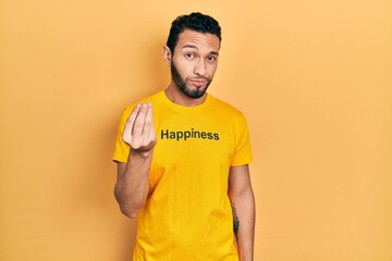 Hispanic man with beard wearing t shirt with happiness word message doing italian gesture with hand...