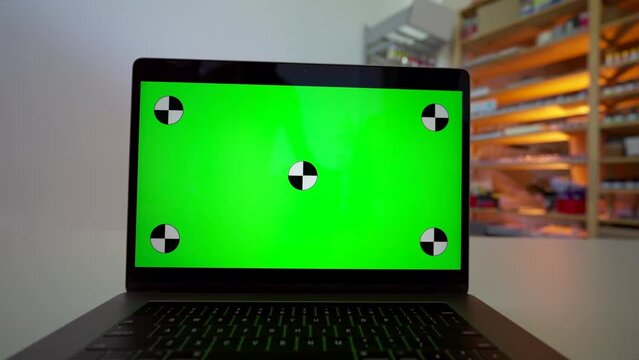 Woman talks on video call via modern laptop on table in shop. Open computer with green chromakey screen at workplace closeup place to insert