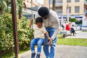 Father and son playing on swing at playground