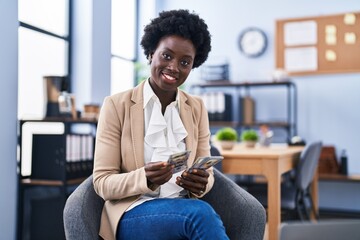 Young african american woman business worker counting dollars sitting on chair at office