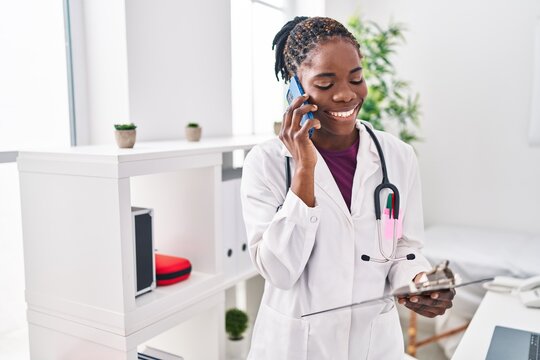 African american woman wearing doctor uniform talking on the smartphone at clinic