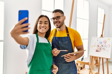 Young hispanic couple smiling happy make selfie by the smartphone at art studio.