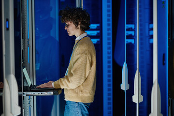 Female technician using laptop while analysing server in large data center