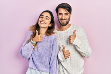 Young hispanic couple wearing casual clothes success sign doing positive gesture with hand, thumbs...