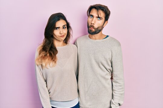 Young hispanic couple wearing casual clothes making fish face with lips, crazy and comical gesture. funny expression.