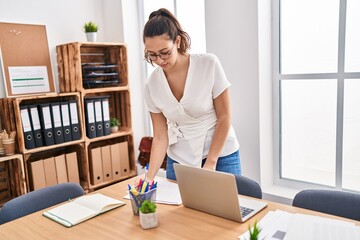 Young beautiful hispanic woman business worker writing on document standing at office