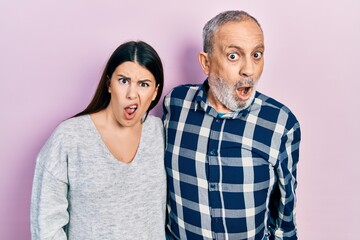 Hispanic father and daughter wearing casual clothes in shock face, looking skeptical and sarcastic, surprised with open mouth