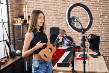 Fototapeta na wymiar Adorable girl musician having ukulele online class at music studio
