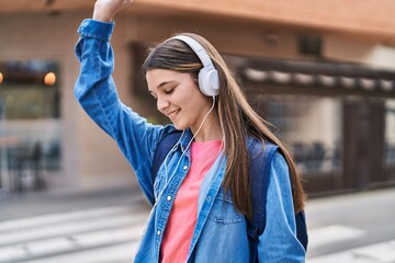 Adorable girl student listening to music at street