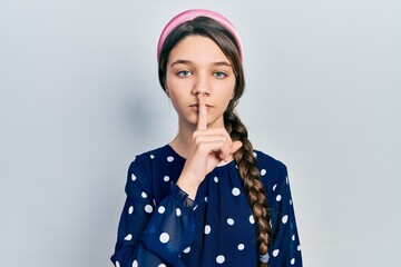 Young brunette girl wearing elegant look asking to be quiet with finger on lips. silence and secret concept.