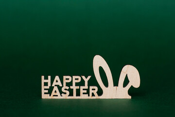 Wooden inscription Happy Easter and stylized bunny ears on a green background - 519198347