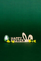 Wooden inscription Happy Easter, stylized bunny ears on a dark green background - 519198589