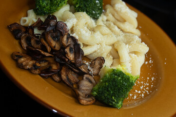 fried mushrooms with brocolli and pasta on a brown plate