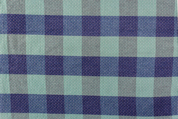 Blue and green cells, the texture of checkered fabric as a background. Fabric shirt in a cage. Repetitive geometric pattern with intersecting lines, squares. Abstract pattern.