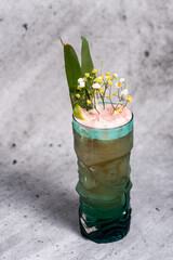 Beautiful cocktail garnished with lime and flowers on a concrete background