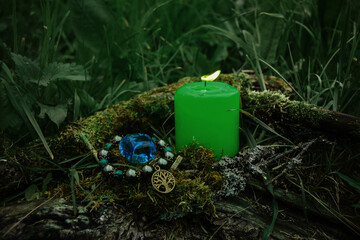 burning green candle, a symbol of the moon, an amulet lying on a moss on a dark natural background....
