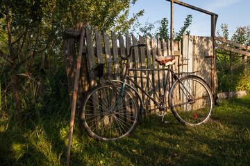 Obraz premium An old bicycle is parked near a wooden fence. Rural motif