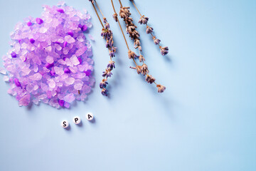 Purple bath salt and lavender on a blue background. Space for text. Spa inscription.