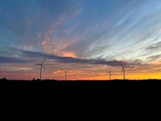 Fototapeta na wymiar Orange sunset with purple cloud in the landscape, black silhouette of the windmills