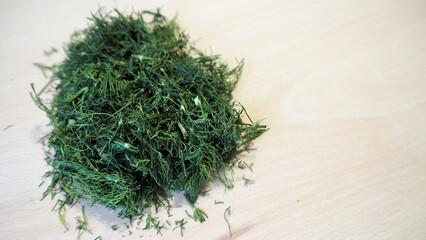 on a wooden board, there is chopped dried green dill . top view. cooking aromatic spices at home