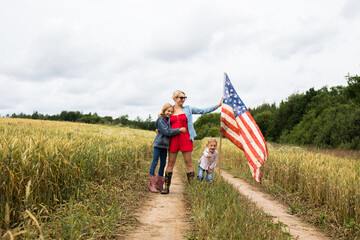 Girl with children on the field stands with a USA flag