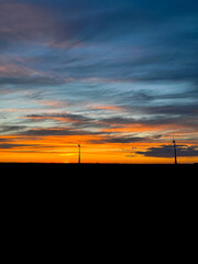 Orange sunset with purple cloud in the landscape, black silhouette of the windmills