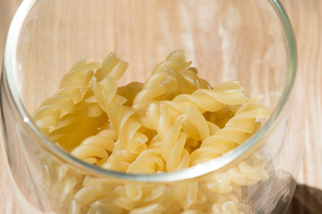 Spiral pasta in a glass bowl on the kitchen table.