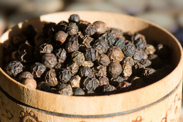 Dried seeds black pepper (Piper nigrum) in the wooden cup. Ingredient for spices. Culinary background texture. Top view.