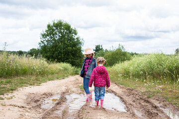 Two girls run through the puddles and play.