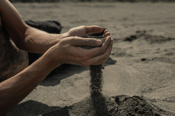 Man pouring sand through hands in desert