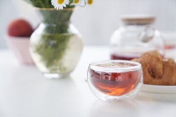 Transparent glass Cup of tea in nature. The concept of breakfast in the backyard of the house. Early morning, tea and kettle. In the cup you can see the reflection of the sky and a one-story house.